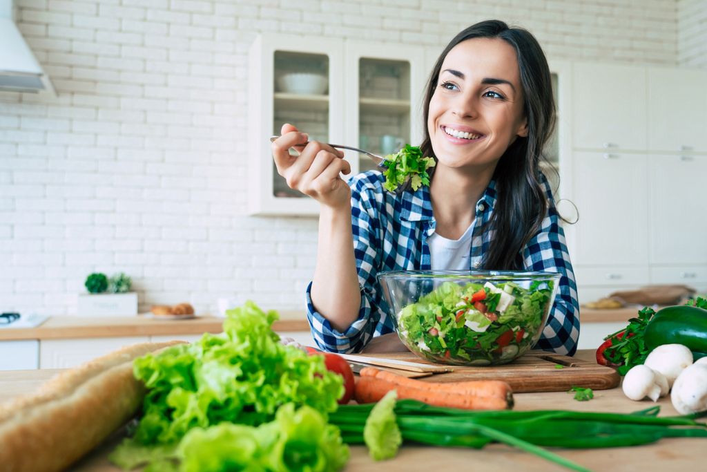 mujer sonriente comiendo alimentos saludables