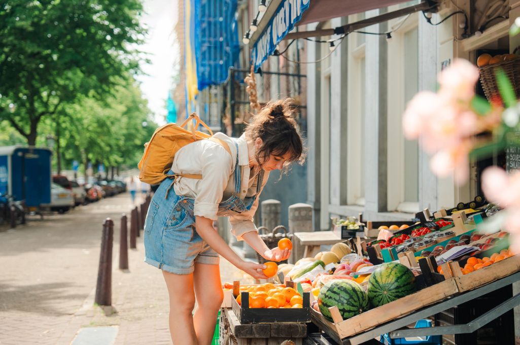 mujer seleccionando fruta y verdura en una tienda a pie de calle