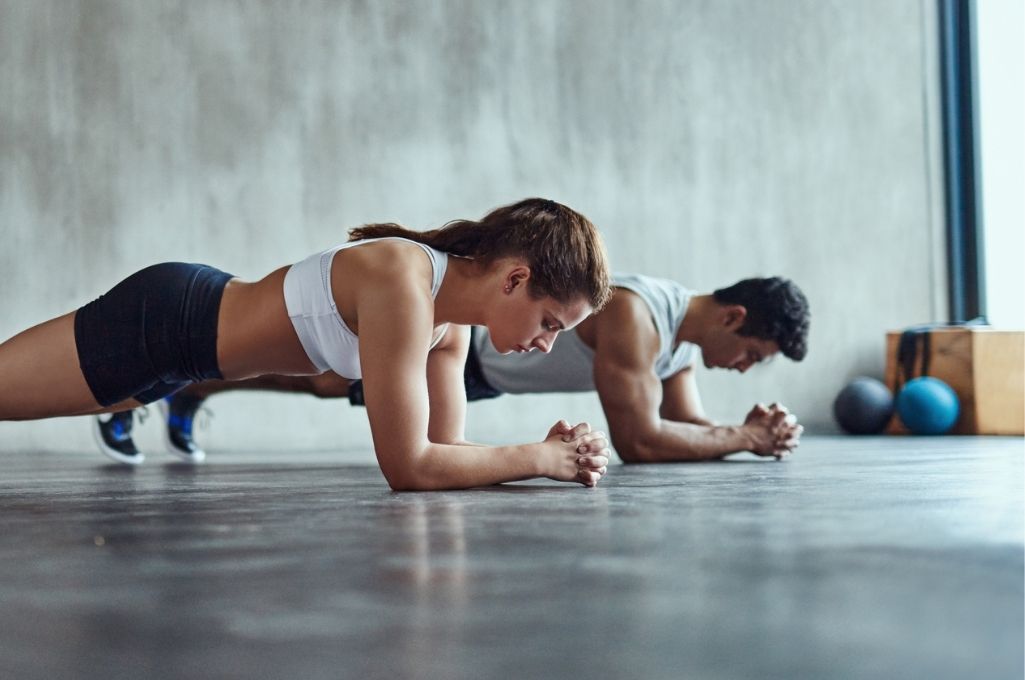 mujer y hombre haciendo la plancha en un gimnasio